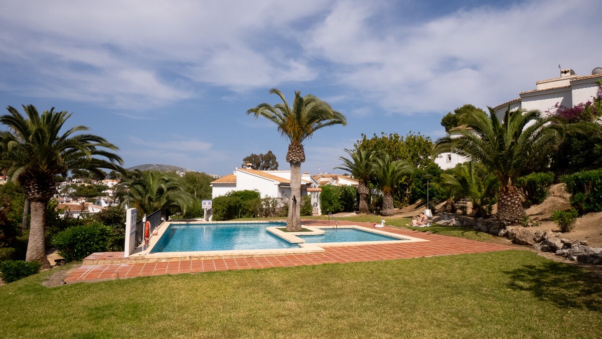 Shared pool surrounded by lawn and pine trees