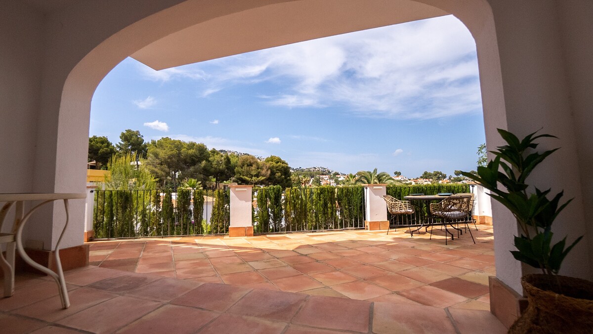 The covered terrace with table and chairs looking out toward the valley